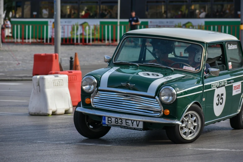 a small green and white car driving down a street, by Sven Erixson, unsplash, in a race competition, mini, older male, posing elegantly