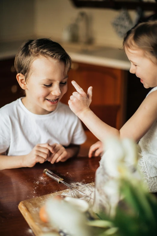 a couple of kids that are sitting at a table, by Elizabeth Durack, pexels, flour dust flying, on kitchen table, medium close up shot, instruction