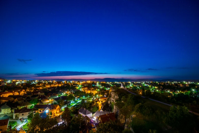 a view of a city at night from the top of a hill, shipibo, blue sky, drone photograpghy, vibrant hues