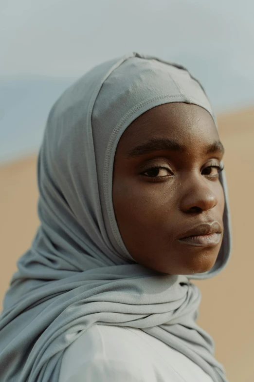 a woman wearing a headscarf in the desert, by Alasdair Grant Taylor, trending on unsplash, light skinned african young girl, film promotional still, neutral focused gaze, in an arena in movie dune-2021