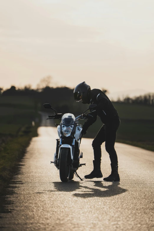 a person standing next to a motorcycle on a road, profile image