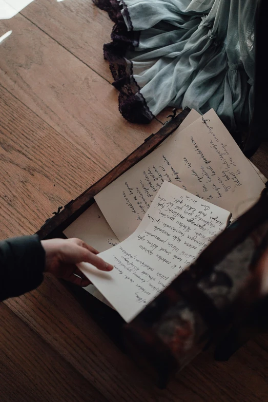 a person holding a piece of paper next to a suitcase, by Emma Andijewska, unsplash, ancient writing, in a dusty victorian home, slide show, a high angle shot