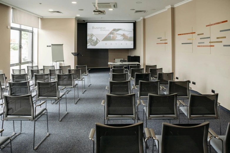 a room filled with chairs and a projector screen, central hub, corporate, biological, soft natural light