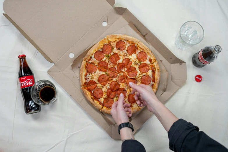 a person reaching for a pepperoni pizza in a box, by Julia Pishtar, pexels contest winner, everything enclosed in a circle, gaming, on a gray background, on a table