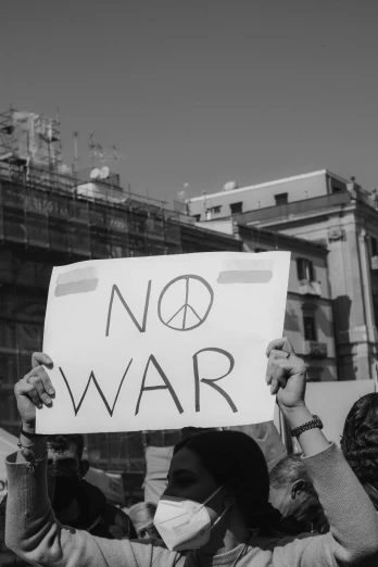 a person holding a sign that says no war, a black and white photo, pexels contest winner, neoism, alternate album cover, rome, bomb, world peace