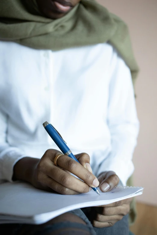 a close up of a person writing on a piece of paper, jemal shabazz, multiple stories, muslim, androgynous person