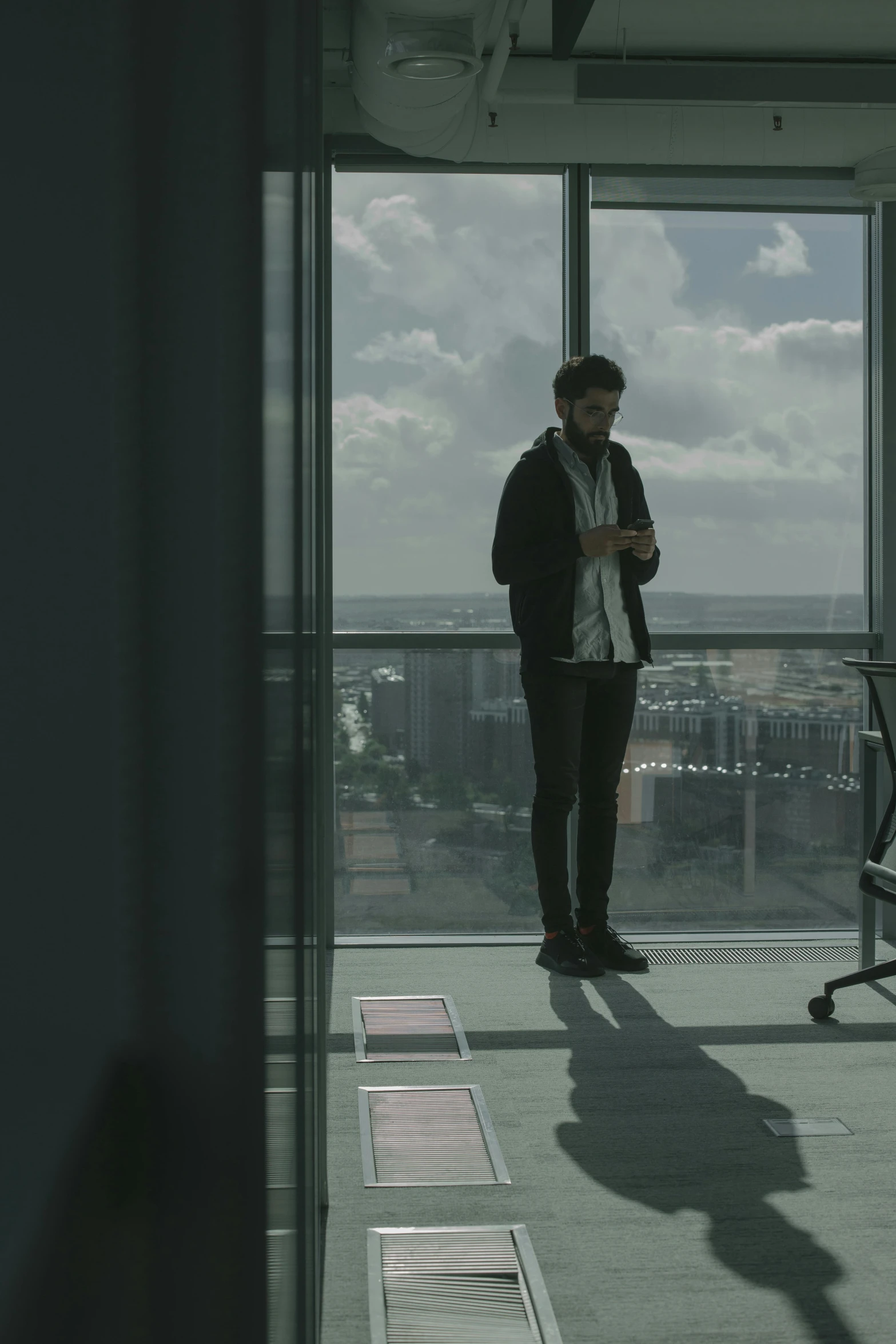 a man standing in an office looking out a window, unsplash, serial art, still from a music video, smartphone footage, ignant, mark edward fischbach