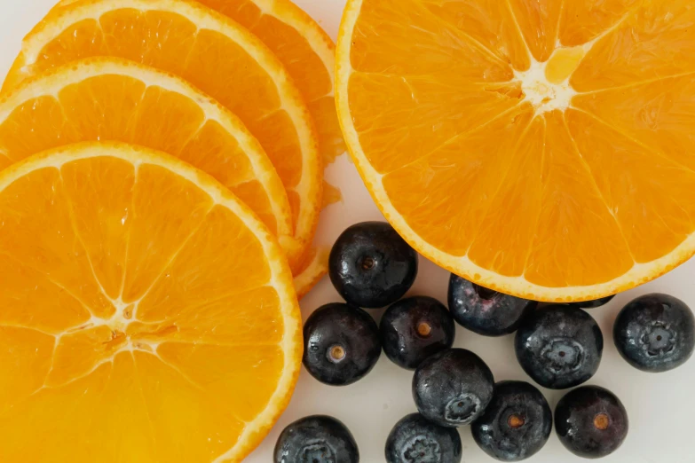 a white plate topped with orange slices and blueberries, by Carey Morris, pexels, background image, grey orange, 🦩🪐🐞👩🏻🦳, ingredients on the table