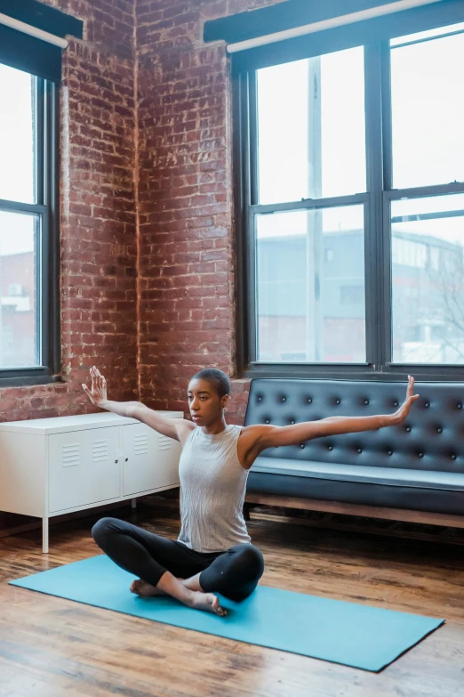 a woman sitting on a yoga mat in a living room, by Carey Morris, trending on unsplash, arabesque, with arms up, square, low quality photo, dwell