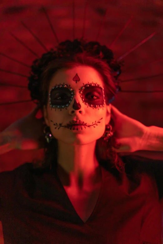 a woman in day of the dead makeup holding an umbrella, an album cover, inspired by Elsa Bleda, pexels contest winner, cinematic and dramatic red light, square, dia de los muertos. 8 k, low quality photo