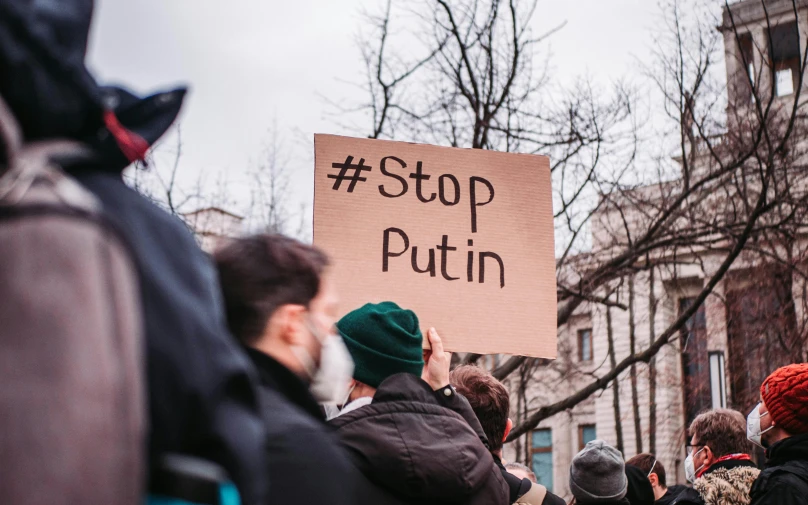 a group of people holding a sign that says stop putin, a photo, by Julia Pishtar, shutterstock, instagram post, on a canva, seen from the back, warm