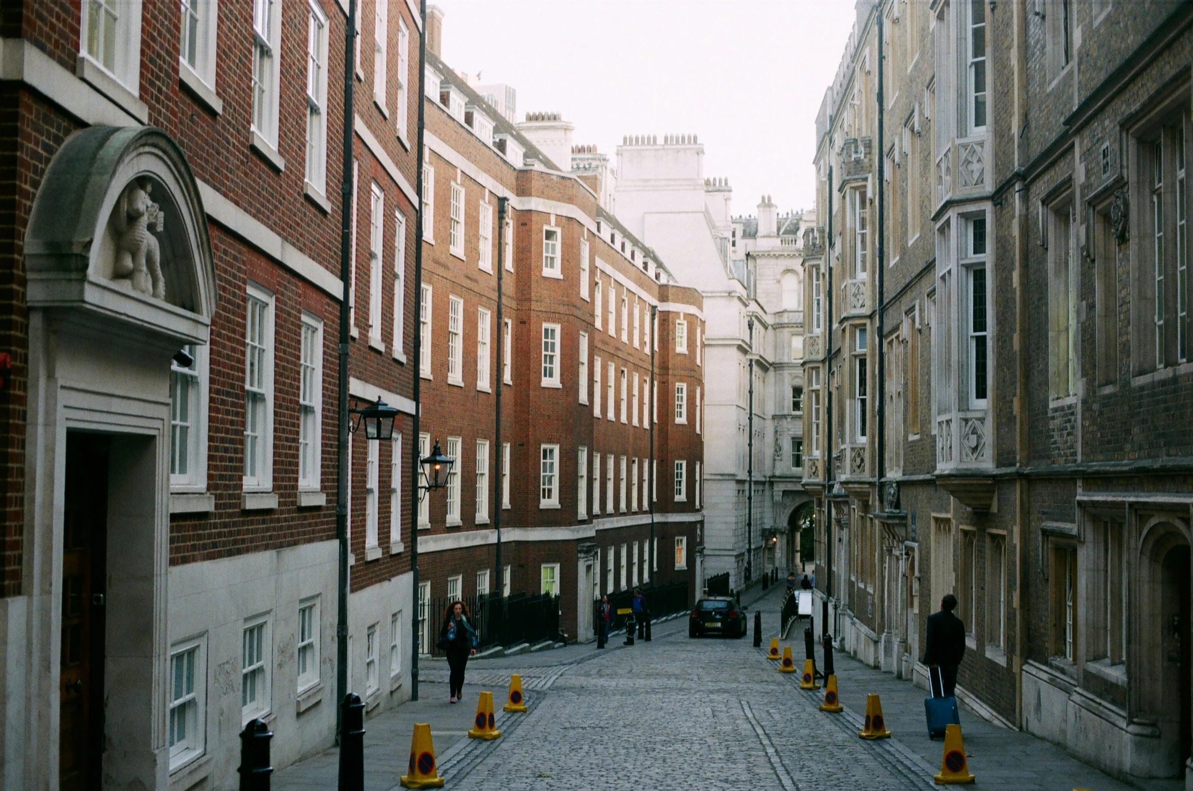 a couple of people walking down a cobblestone street, inspired by Thomas Struth, unsplash, renaissance, nineteenth century london, 2000s photo, tenement buildings, mustard