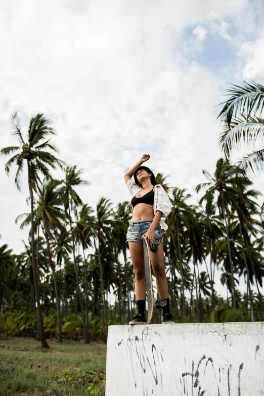 a woman standing on top of a cement block, coconut trees, wearing shorts, islandpunk, 5 0 0 px models