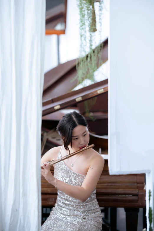 a woman in a silver dress playing a violin, inspired by Zheng Xie, unsplash, standing on top of a piano, next to window, wedding, a young asian woman