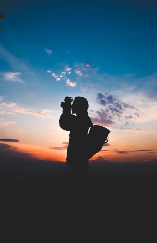 a silhouette of a person holding a surfboard at sunset, pexels contest winner, holding a big camera, full body potrait holding bottle, standing on a mountain top, holding a camera