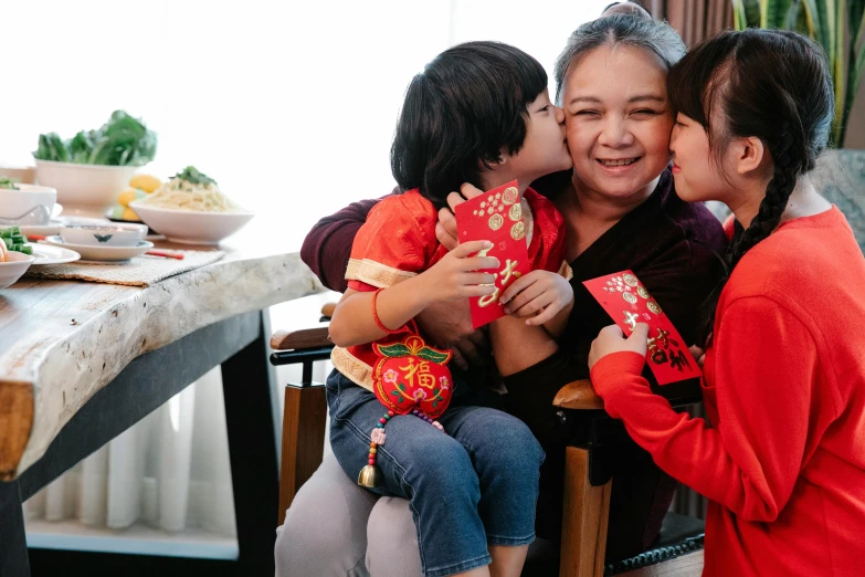 a woman sitting on top of a chair next to a little girl, inspired by Cui Bai, pexels contest winner, happening, dressed in red paper bags, kissing each other, family dinner, wearing authentic attire