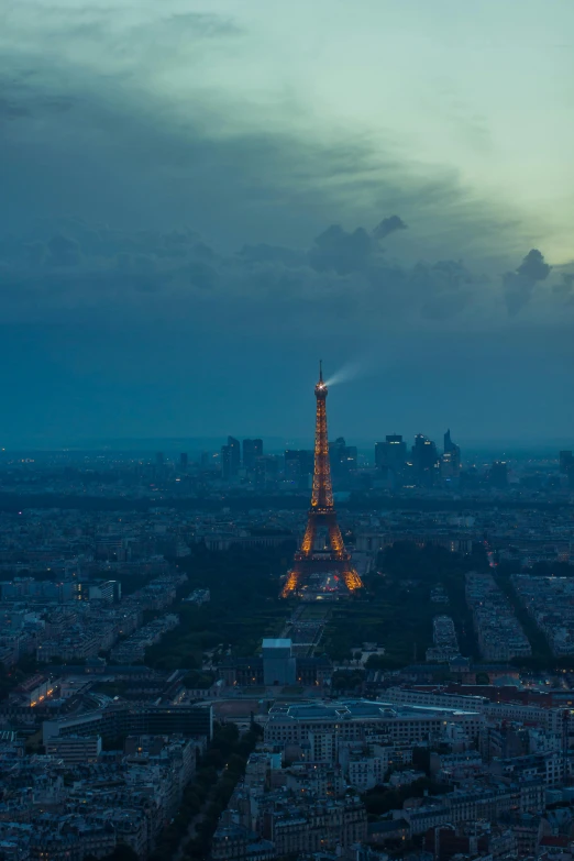 the eiffel tower is lit up at night, an album cover, unsplash contest winner, helicopter view, paul barson, overcast dusk, panorama