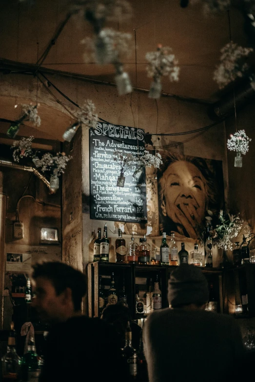 a group of people sitting at a bar, by Tobias Stimmer, pexels contest winner, art nouveau, flowers around, graffiti and posters on the wall, winter, cafe lighting