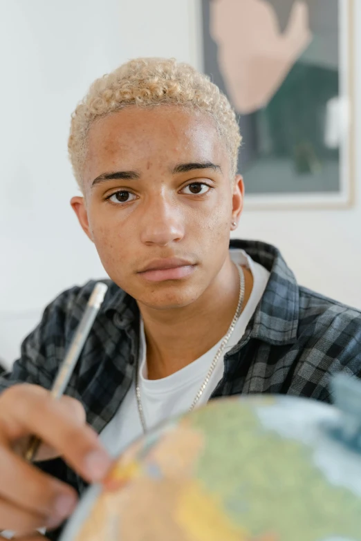 a young man holding a pen and looking at a globe, an album cover, by Cosmo Alexander, ashteroth, nonbinary model, nft portrait, blond boy