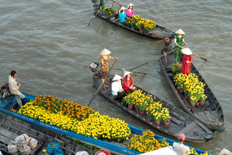 a group of people riding on top of boats filled with flowers, hoang lap, avatar image, high-resolution photo