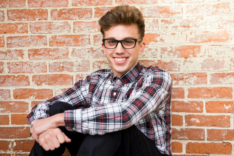 a young man sitting in front of a brick wall, shutterstock, big glasses, portrait image, max prentis, square