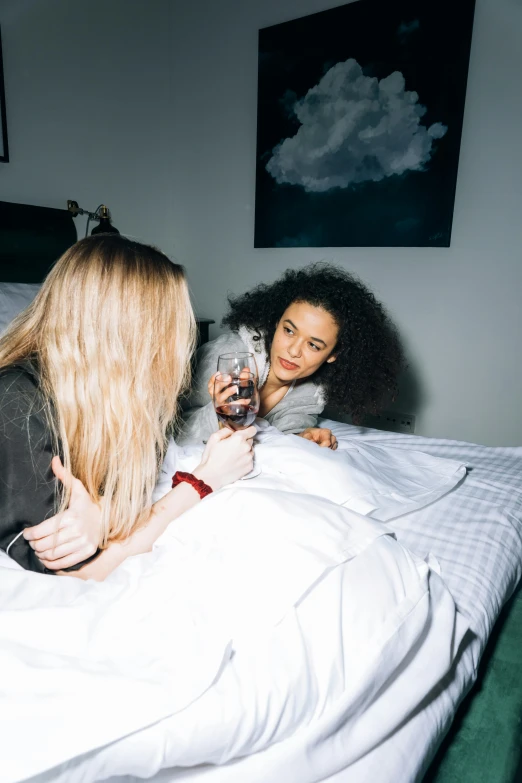 a couple of women sitting on top of a bed, inspired by Nan Goldin, trending on pexels, happening, drinking and smoking, doja cat, high angle, profile image