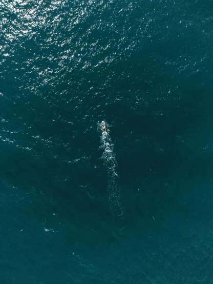 a person on a surfboard in the middle of a large body of water, pexels contest winner, looking down from above, deep blue ocean color, ignant, slightly pixelated