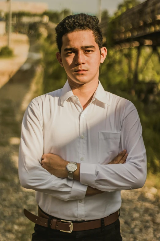 a man in a white shirt standing with his arms crossed, by Alejandro Obregón, pexels contest winner, around 1 9 years old, wearing business casual dress, dzung phung dinh, front lit