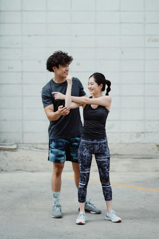 a man and a woman standing next to each other, by Jang Seung-eop, pexels contest winner, wearing fitness gear, reaching out to each other, square, casual pose