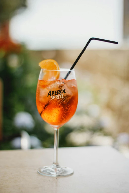 a drink sitting on top of a table, sparkling spirits, al fresco, with a straw, vibrant orange