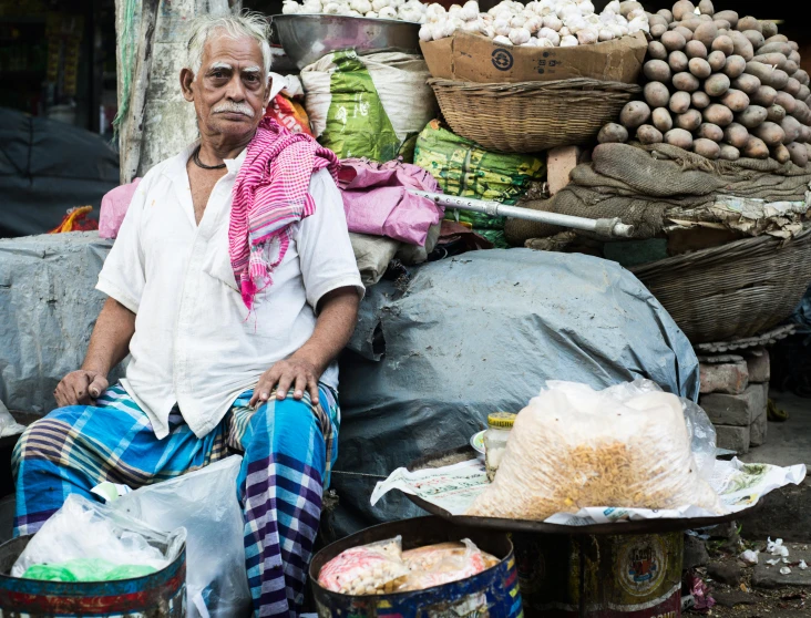 a man sitting in front of a pile of food, a portrait, pexels contest winner, calcutta, quirky shops, mean smirk, an ancient