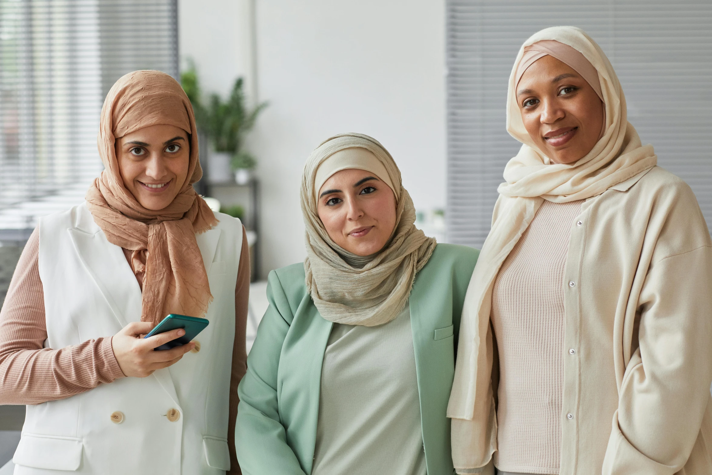 a group of three women standing next to each other, trending on pexels, hurufiyya, white hijab, medium skin tone, in an office, fan favorite