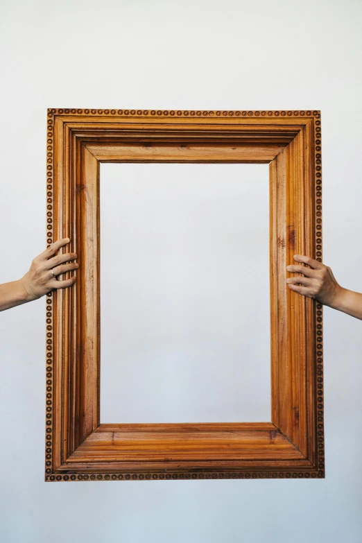 two people holding a picture frame in their hands, by Everett Warner, pexels contest winner, visual art, symmetrical framing, professional woodcarving, tall thin frame, hyperrealistic