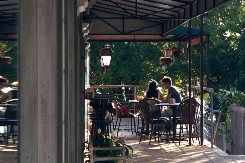 a couple of people that are sitting at a table, by Meredith Dillman, unsplash, realism, patio, quaint, lachlan bailey, panoramic shot