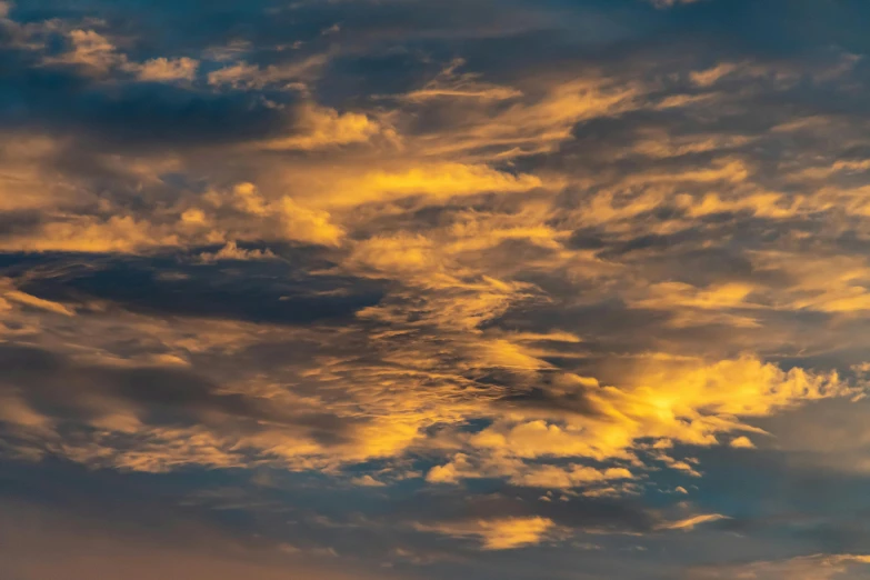 a plane flying through a cloudy sky at sunset, by Neil Blevins, pexels contest winner, romanticism, dappled golden sunset, layered stratocumulus clouds, today\'s featured photograph 4k, orange yellow ethereal