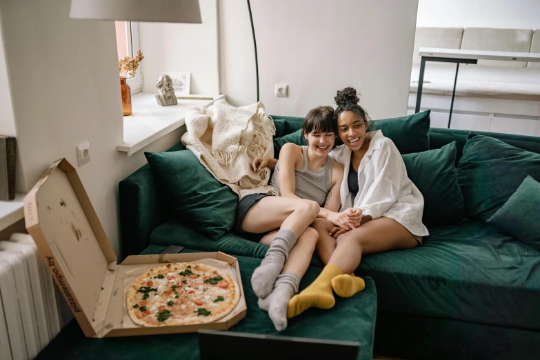 a couple of women sitting on top of a green couch, pexels contest winner, renaissance, pizza, everything fits on the screen, college students, at home