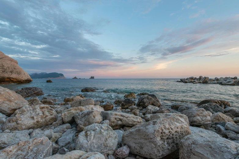 a rocky beach at sunset with rocks in the foreground, by Alexander Fedosav, unsplash contest winner, capri coast, panorama, grey, pink