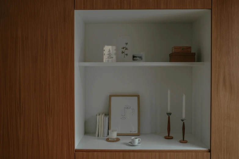 a shelf with candles and a picture on it, inspired by Reinier Nooms, unsplash contest winner, light and space, wood cabinets, soft render, recessed, wood and paper