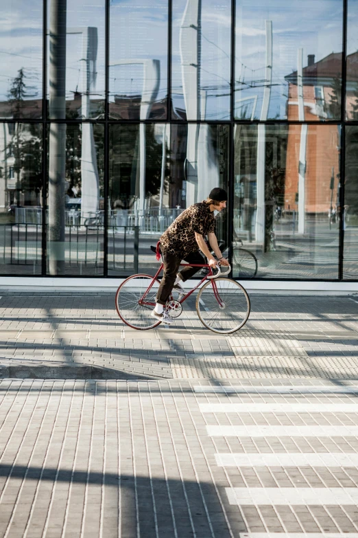 a man riding a bike past a tall glass building, pexels contest winner, streetwear, college, spanish, high resolution image