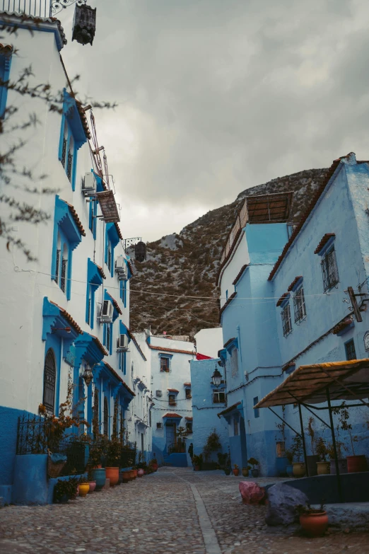 a narrow cobblestone street lined with blue buildings, inspired by Alberto Morrocco, unsplash contest winner, white houses, gif, square, built on a steep hill