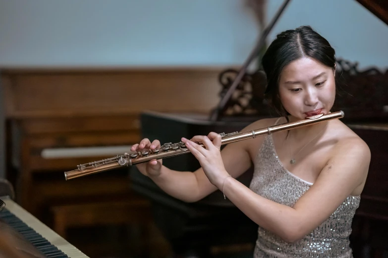 a woman playing a flute in front of a piano, inspired by Zheng Xie, pexels contest winner, live performance, profile image, roberto ferri and ruan jia, sydney hanson