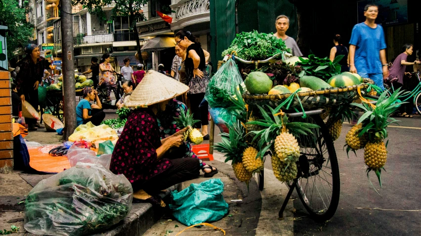 a woman sitting in front of a cart filled with pineapples, by Sam Dillemans, trending on unsplash, busy streets filled with people, ao dai, square, greens)