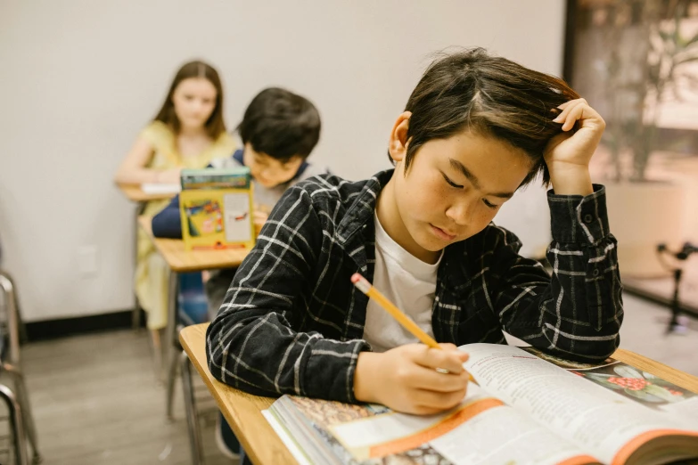 a boy sitting at a desk with a pencil in his hand, pexels contest winner, jin shan and ross tran, center focused, trying to read, school curriculum expert