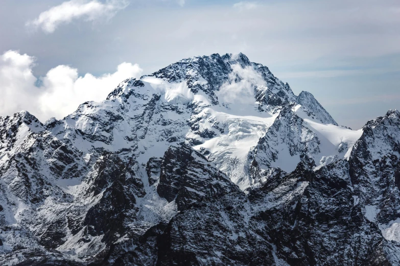 a group of mountains covered in snow under a cloudy sky, an album cover, by Sebastian Spreng, pexels contest winner, hurufiyya, towering high up over your view, high angle close up shot, the photo shows a large, craggy