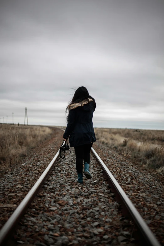 a woman walking on train tracks in the middle of nowhere, by Lucia Peka, unsplash, asian girl, steppe, trauma, profile pic