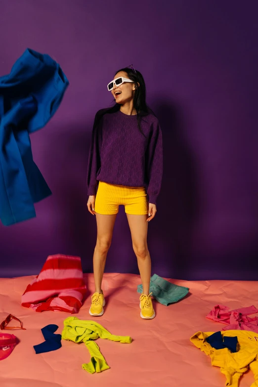 a woman standing in front of a pile of clothes, pexels contest winner, color field, wearing a purple sweatsuit, in shorts, yellow carpeted, promotional image