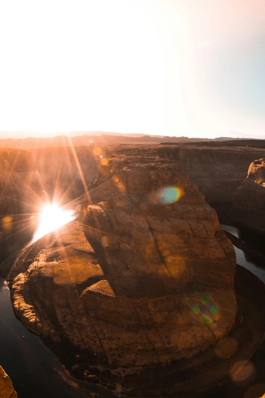 a man standing on top of a cliff next to a river, pexels contest winner, symbolism, grand canyon | golden hour, hot sun from above, rock arcs, sunset panorama