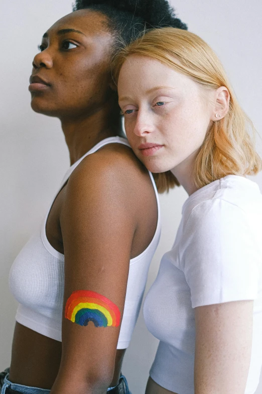 a couple of women standing next to each other, by Arabella Rankin, trending on pexels, renaissance, still of rainbow ophanim, bandage on arms, androgyn beauty, primary colors are white