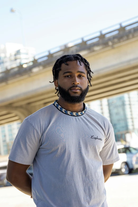 a man with dreadlocks standing in a parking lot, teddy fresh, wearing tight shirt, on a bridge, headshot