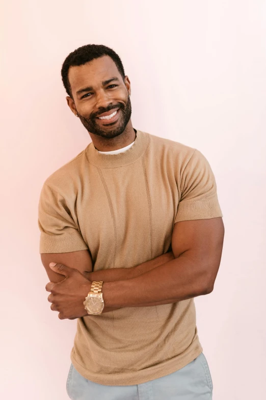 a man in a tan shirt standing with his arms crossed, inspired by Charles Alston, trending on pexels, smiling fashion model, chest hair, cast, romantic lead